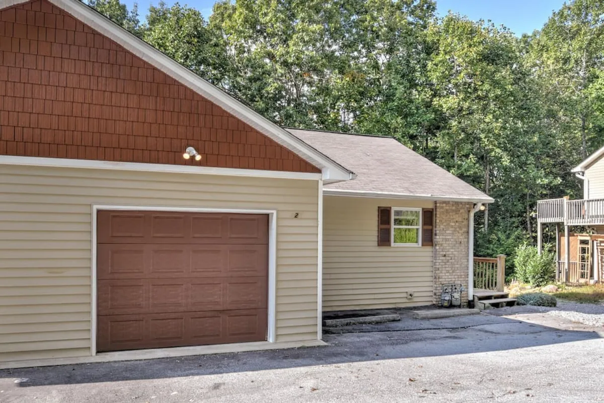 This exterior shot presents the garage door with a window and roof shingles, set in a welcoming outdoor environment. The image emphasizes both the accessibility of garage parking and a pleasant, well-maintained exterior, reinforcing convenience for guests arriving by car.